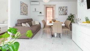 Ein modernes Wohnzimmer mit einer Couch, einem Esstisch, Stühlen und einem Fernseher.
