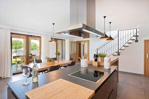 A modern kitchen with a central island, pendant lighting, and a staircase leading to an upper level. - Villa with pool and air conditioning (Poreč)