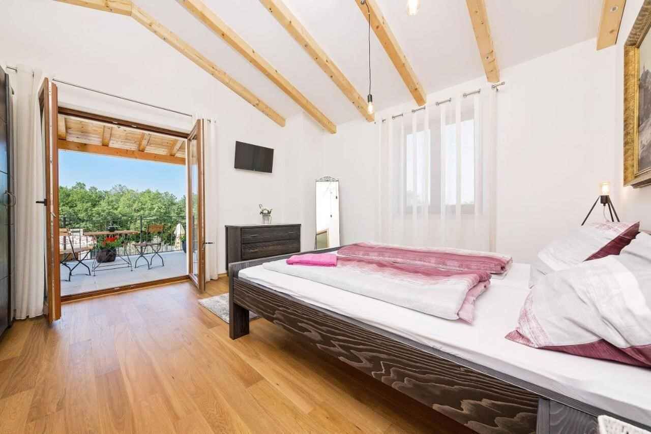 Ein Schlafzimmer mit Holzboden, einem Bett mit rosa und weißer Bettwäsche, einem Schminktisch und Blick auf Grünflächen außerhalb.
