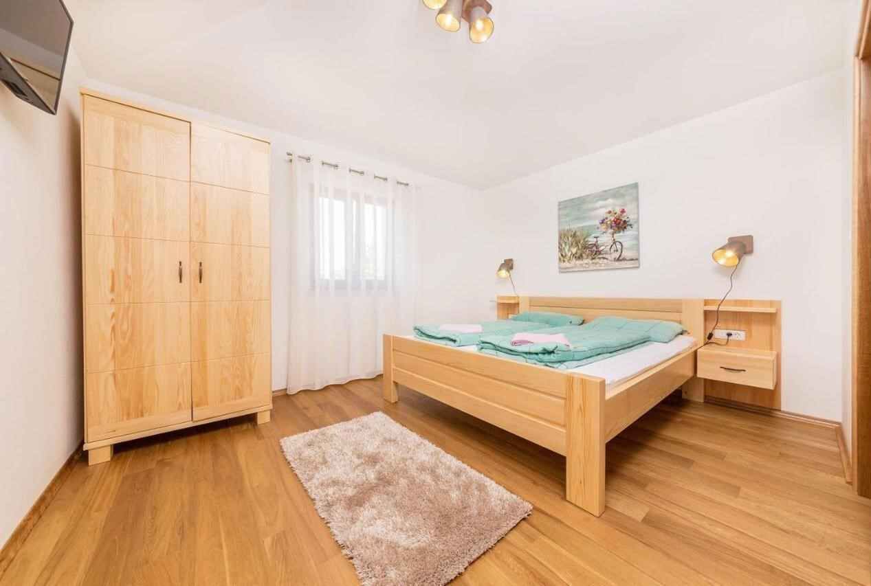 A bedroom with a wooden bed, a wardrobe, a bedside table, and a nightstand.