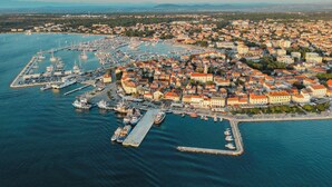 Vista aérea de un pueblo costero con un puerto deportivo, edificios y un muelle.
