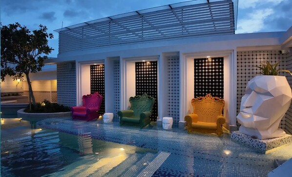 A modern building with a pool, multiple chairs, and a large sculpture. - Stallionz by KLIQ (Ipoh)