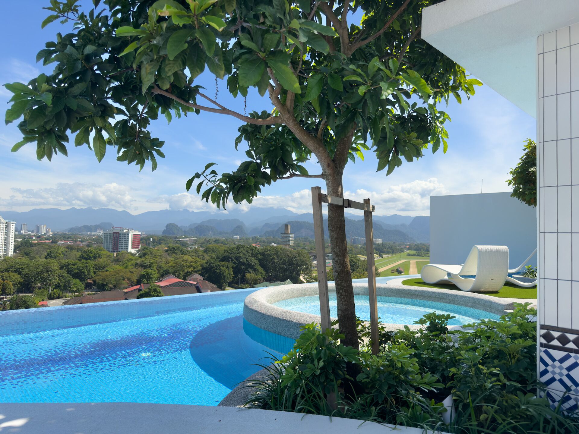 Piscina com vista para montanhas e edifícios ao fundo.
