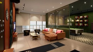 Un espace de détente moderne comprenant un canapé, des fauteuils, une table de billard et un jeu de fléchettes.