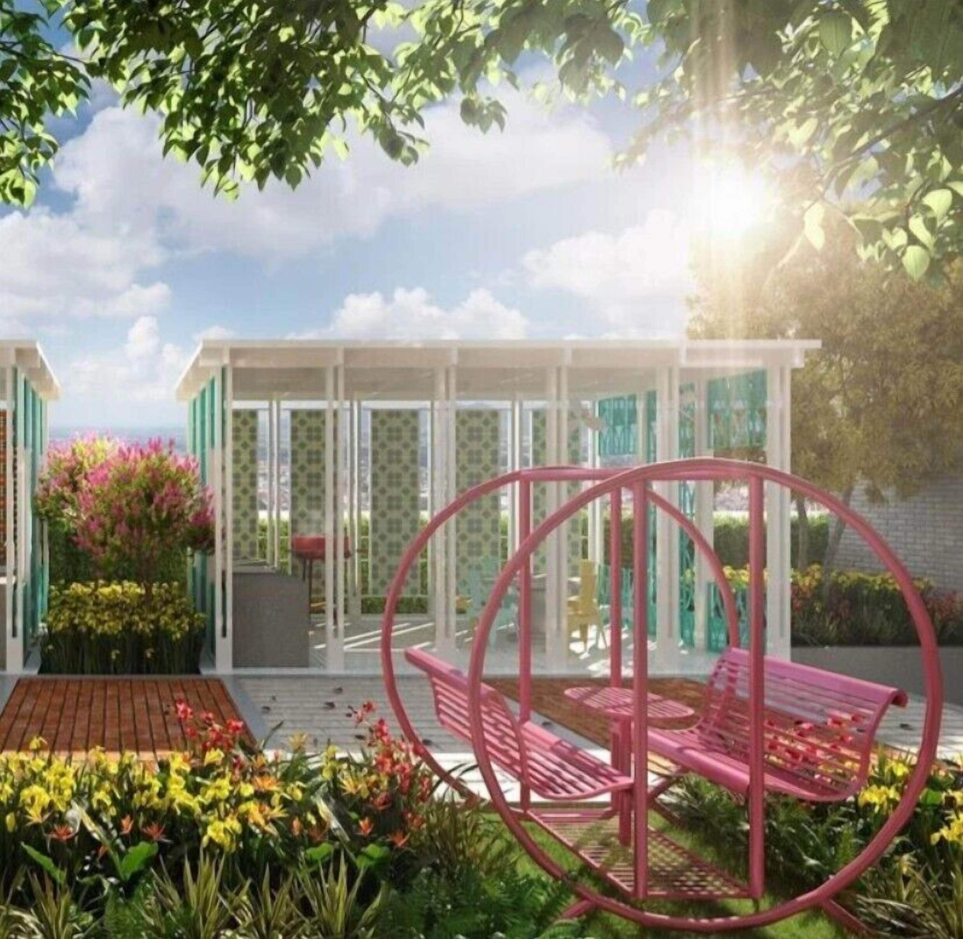 A modern outdoor seating area with a circular metal structure, surrounded by lush greenery and flowers.