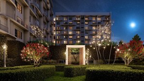 Un hôtel moderne à la façade symétrique, doté de nombreux balcons et d’une entrée bien éclairée.