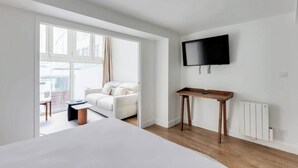 Una habitación de hotel moderna con una cama, un televisor montado en la pared, una pequeña mesa de madera y una silla.