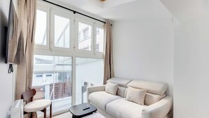 Una sala moderna con un sofá, una silla, una mesita y un televisor.