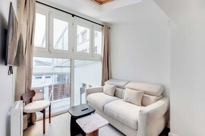 Uma sala de estar moderna com sofá, poltrona, mesa pequena e televisão.