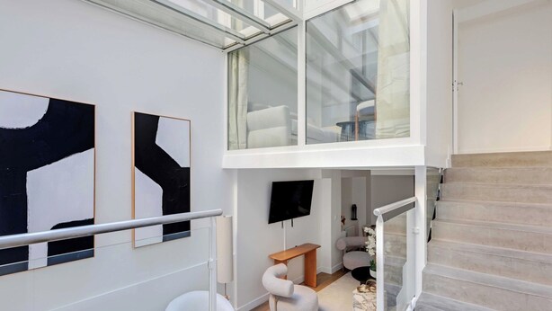 Un interior moderno con una escalera, un televisor de pantalla plana, arte abstracto y una zona de estar.