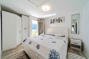 Ein Schlafzimmer mit einem Bett, einem Kleiderschrank, einem Nachttisch, einem Spiegel und einem Fenster mit Blick.