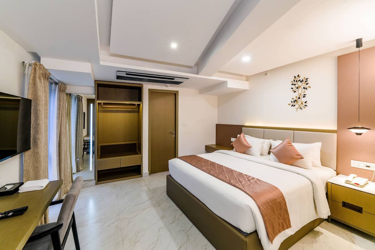 A hotel room with a bed, bedside table, TV, desk, and a wardrobe.
