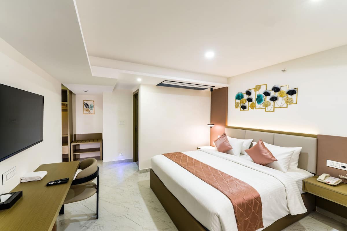 A hotel room with a bed, bedside table, chair, TV, and a wall-mounted artwork.