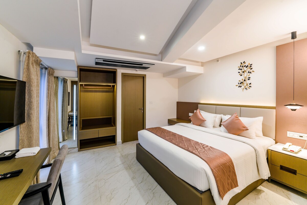 Een hotelkamer met een bed, nachtkastje, televisie, bureau en een kledingkast.