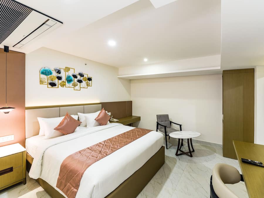 Una habitación de hotel con cama, mesita de noche, silla, escritorio y televisor de pantalla plana.