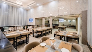 A modern restaurant with multiple dining tables, chairs, and a large TV screen. - Hotel Star Place - Chennai (Chennai)