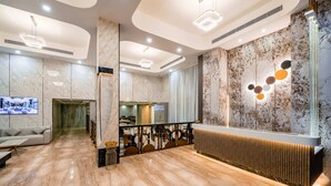 A modern lobby with marble flooring, a reception desk, a seating area with a sofa, and a television screen. - Hotel Star Place - Chennai (Chennai)