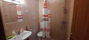 A bathroom with a sink, toilet, shower, and mirror. - Holiday apartment with air conditioning (Keszthely)