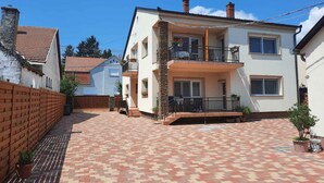 Ein zweigeschossiges Wohngebäude mit einer gefliesten Terrasse.