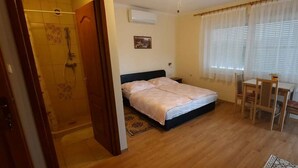 Ein Schlafzimmer mit einem Bett, einem Schreibtisch und einem Stuhl. Es gibt eine Duschkabine mit Glastür.