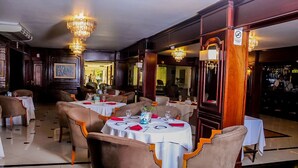 Un restaurant avec des tables rondes, des chaises et des lustres.