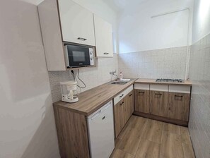 A compact kitchen with a microwave, coffee maker, sink, and wooden cabinets. - Holiday apartment with WLAN and air conditioning (Zamárdi)