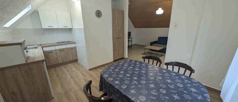 A compact kitchen with wooden cabinets and a dining area with a table covered in a patterned tablecloth.
