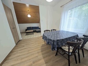 A dining area with a round table, chairs, a sofa, and a wooden ceiling. - Holiday apartment with Wi-Fi, terrace and air conditioning (Zamárdi)