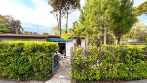 Ein Wohnhaus mit geschlossenem Eingangsbereich, einer kleinen Veranda und einem gepflegten Garten.