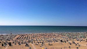 Una spiaggia affollata, con molti ombrelloni e lettini.