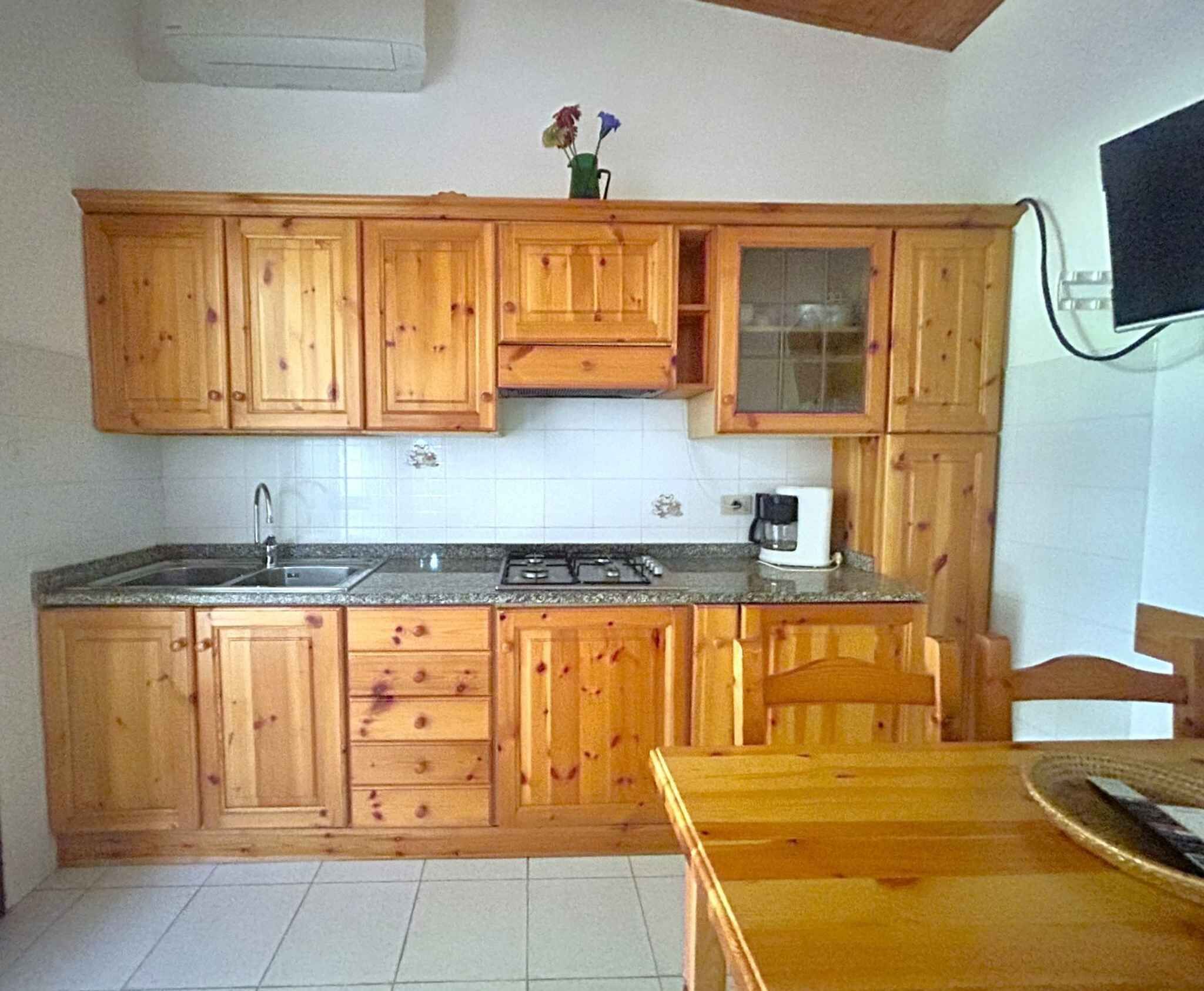 Una cocina con armarios de madera, un lavamanos, una estufa y una cafetera.