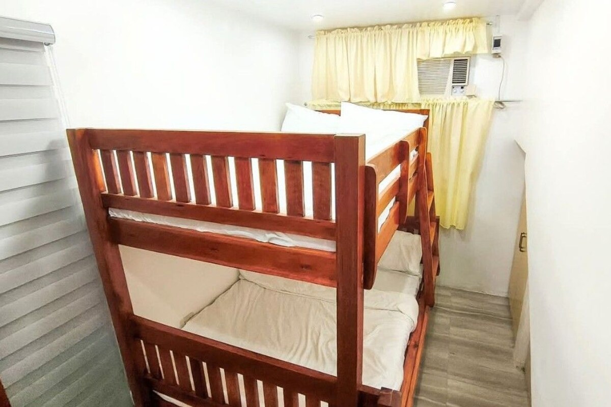A bunk bed room with a window and an air conditioning unit.