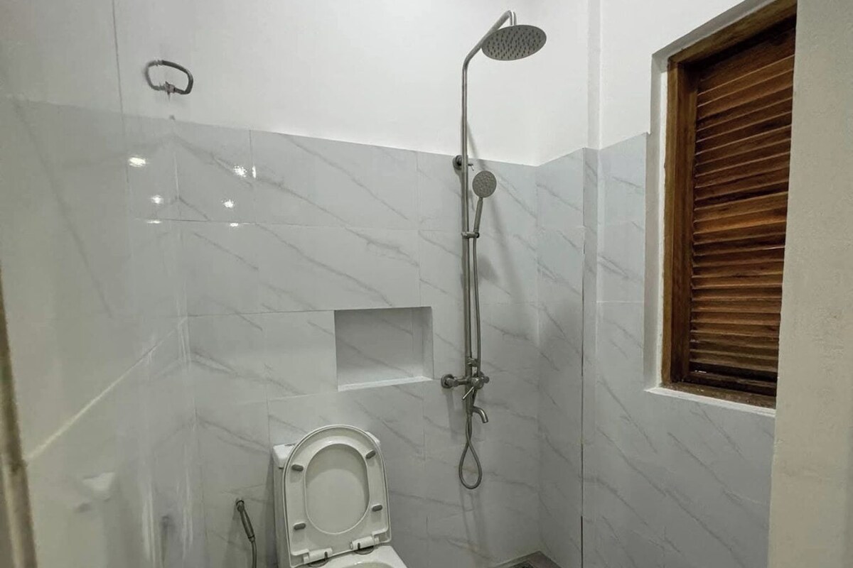 Casa de banho pequena e moderna, com sanita, chuveiro e janela.