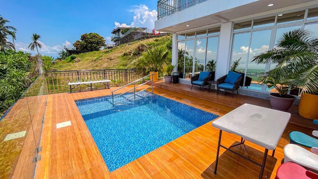 A pool area with a wooden deck, a pool, and a seating area with chairs and a table.