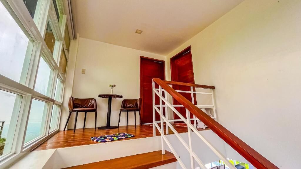 A staircase with wooden steps and a white railing, leading to a room with a red door.