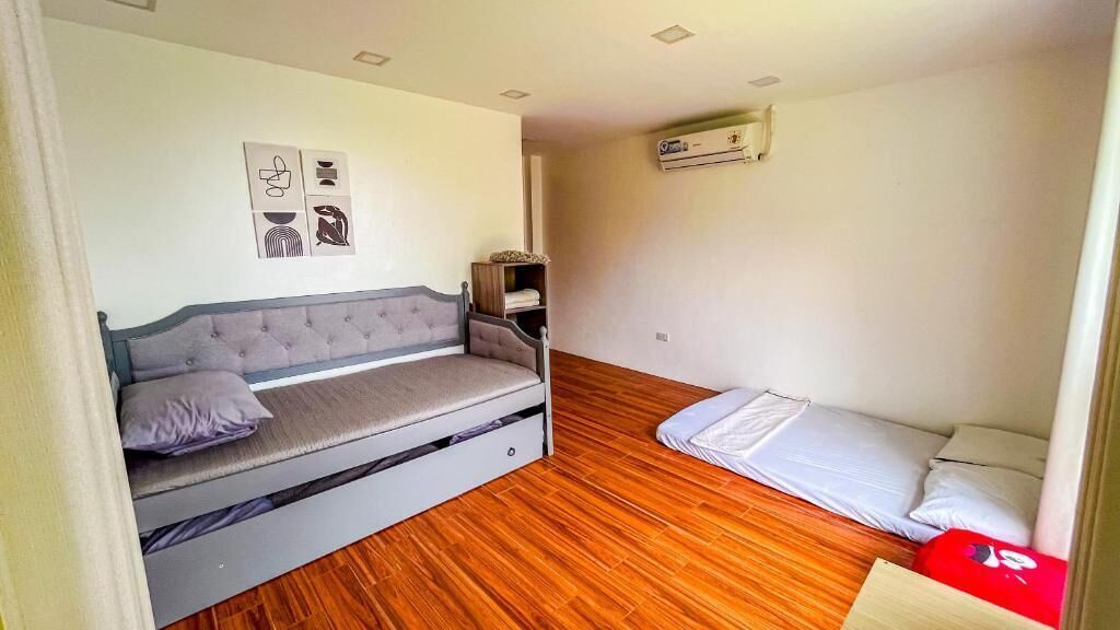 Una habitación con cama, una mesita y aire acondicionado de pared.