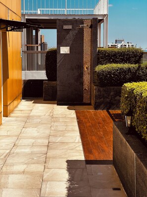 A modern building entrance with a fire exit sign, tiled flooring, and well-maintained hedges. - Cozy 1-bedroom apartment in awesome Pattaya with AC and gym access (pattaya)