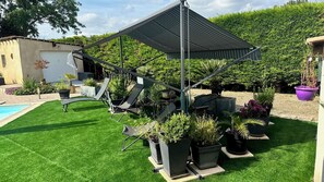 Eine Terrasse mit einer Pergola, Sitzgelegenheiten im Freien und Kübelpflanzen.