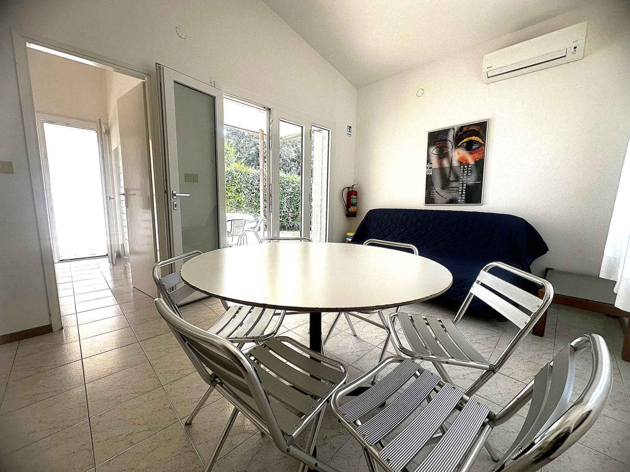 Un coin repas avec une table ronde et des chaises en métal, un canapé bleu et un extincteur fixé au mur.
