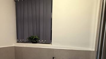 Une salle de bain équipée de toilettes, d’un lavabo et d’une fenêtre avec des rideaux.