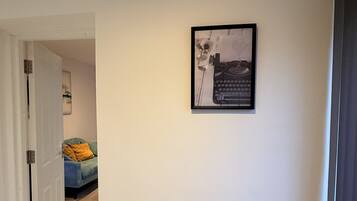 A hallway with a framed picture on the wall, a door leading to another room, and a carpeted floor.