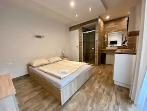 A modern bedroom with a bed, bedside table, and a built-in shower area. - Studio with pool, hot tub and sauna near the free beach (Siófok)