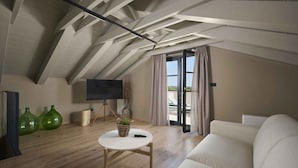 A modern loft bedroom with a sloped ceiling, a large window, a flat-screen TV, a white sofa, and a small round table with a plant. - Villa with pool, only a few minutes from Poreč (Poreč)
