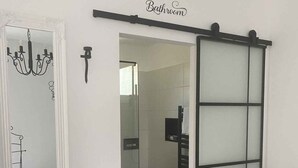 Un baño con puerta corredera, un espejo con candelabro y suelo estampado.