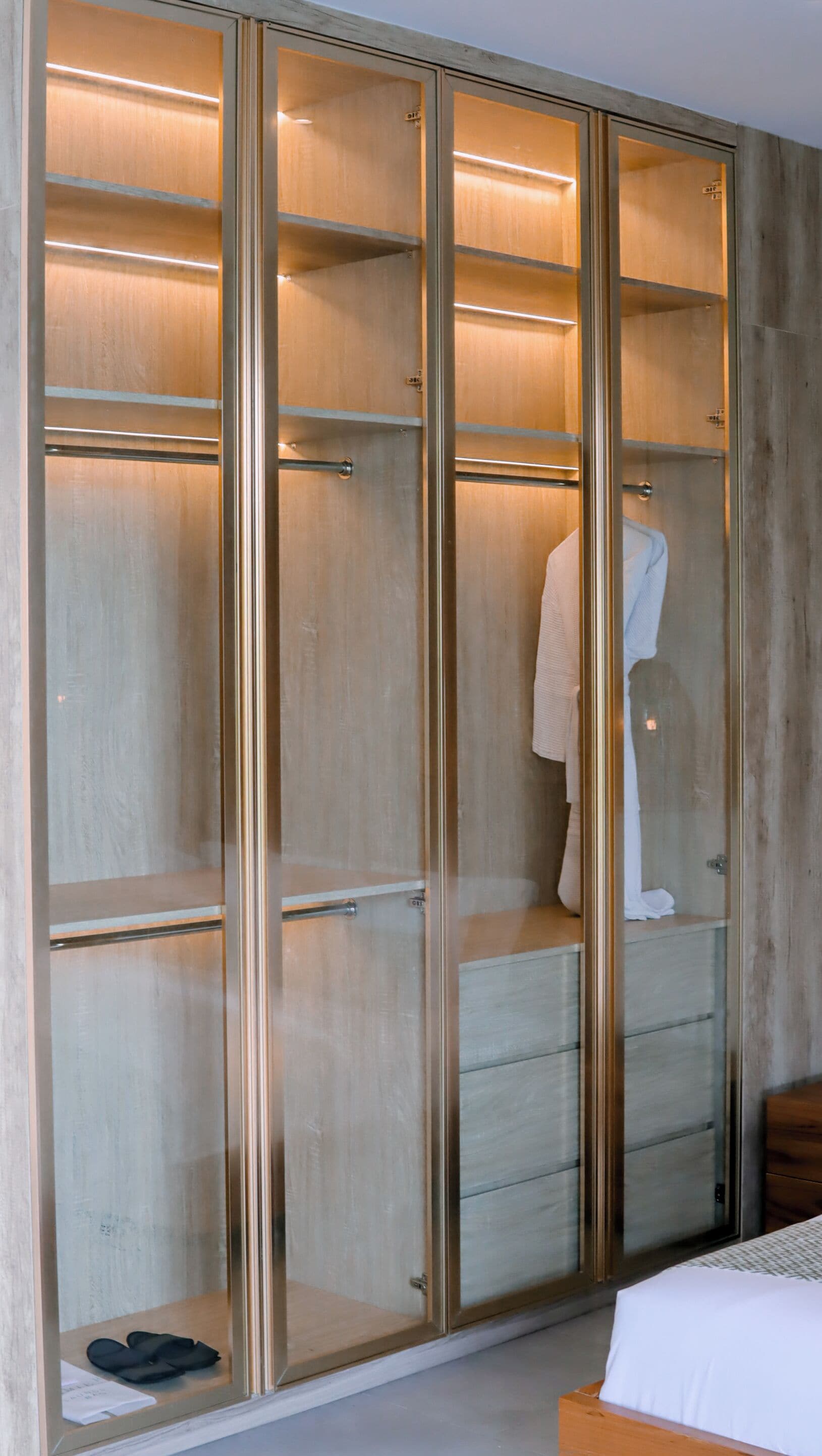 A walk-in closet with multiple shelves and drawers, a mannequin dressed in a robe, and a pair of shoes on the lower shelf.