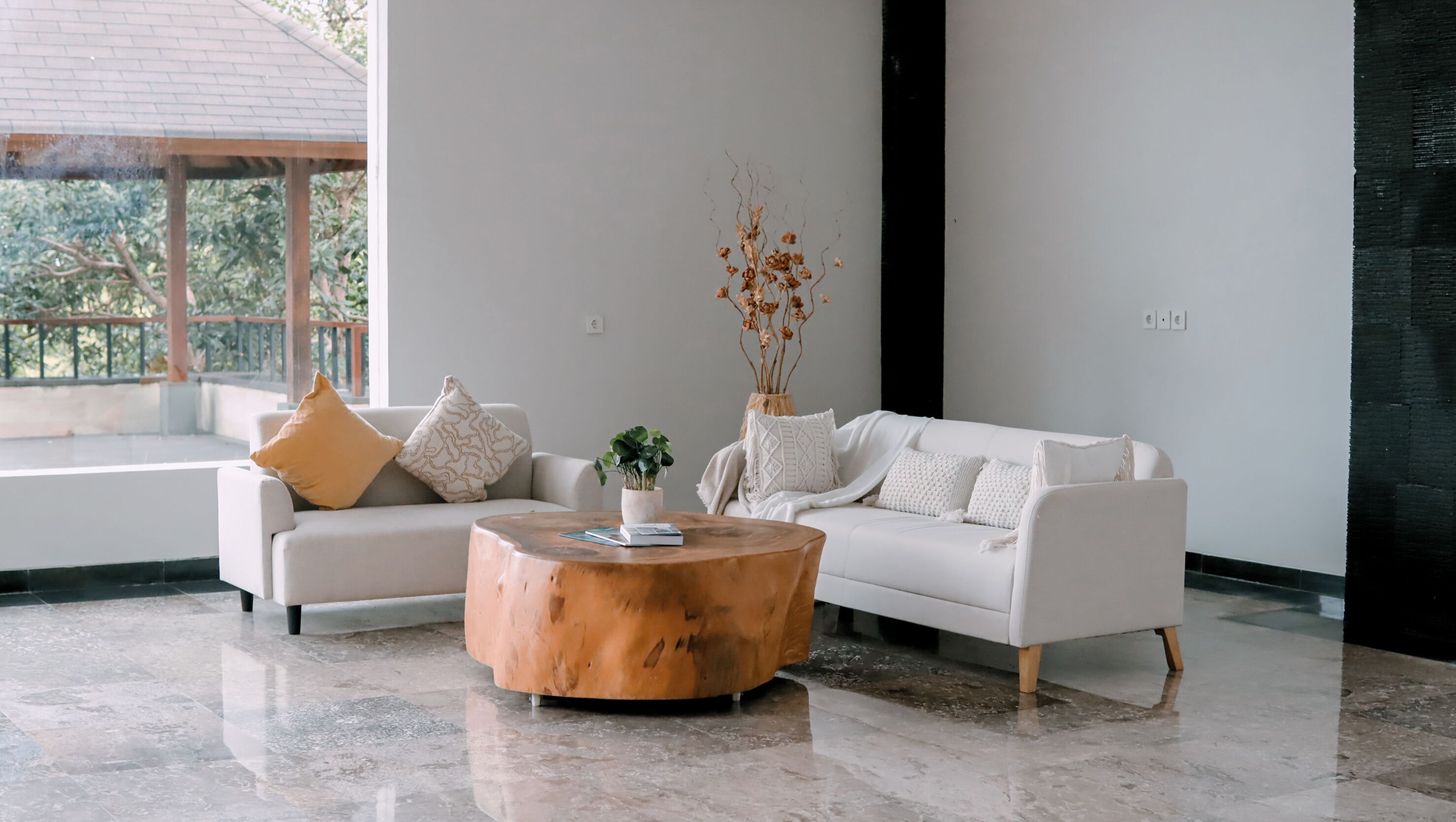 A modern living room with a white sofa, a wooden coffee table, and a potted plant.
