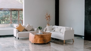 Een moderne woonkamer met een witte bank, een houten salontafel en een potplant.