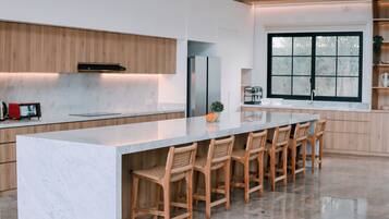 A modern kitchen with a large island, wooden cabinets, and a window with a view.