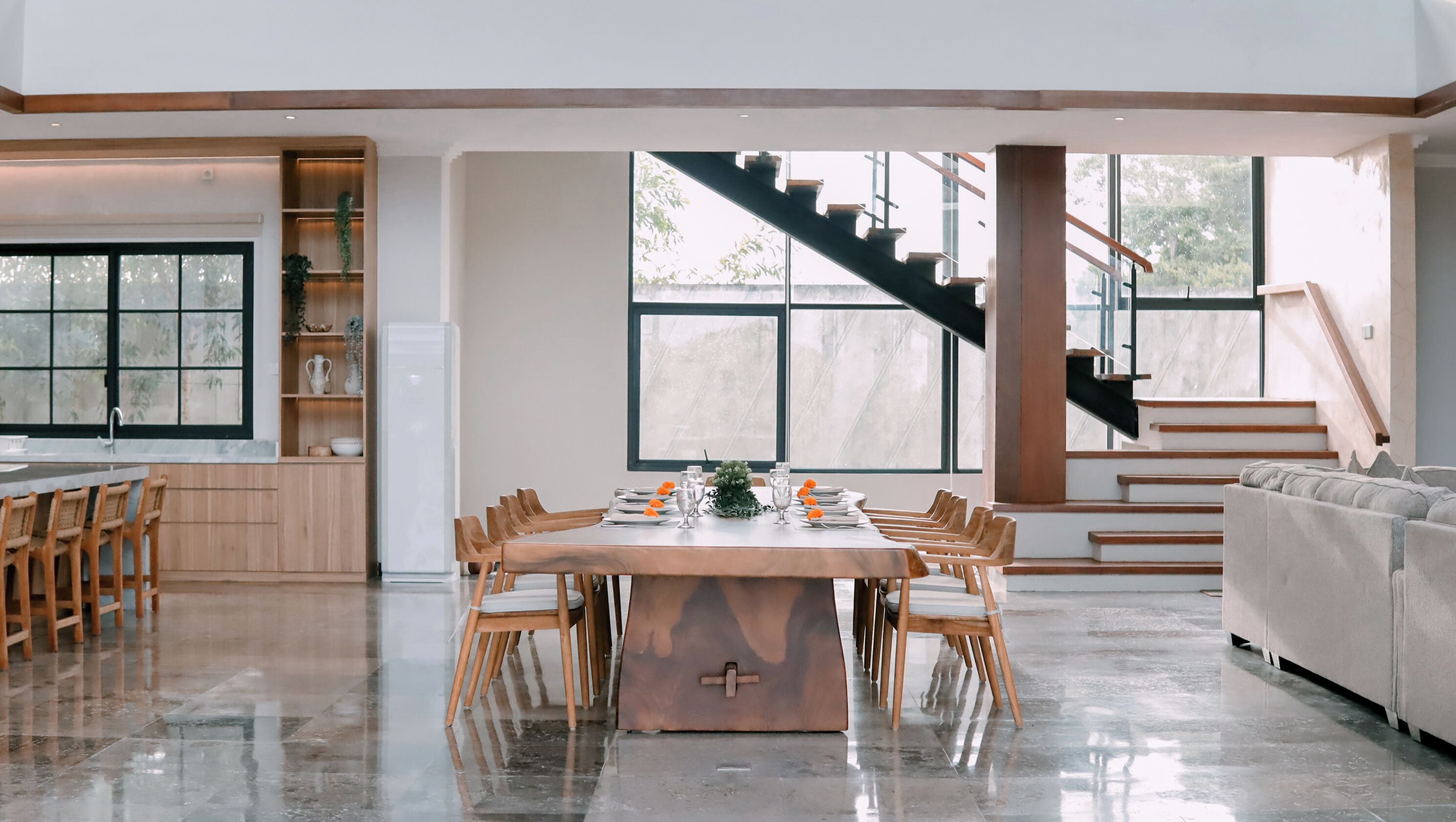 A spacious living area with a dining table, chairs, a sofa, and a staircase.