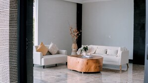 A modern living room with a white sofa, a wooden coffee table, and a vase with dried branches.